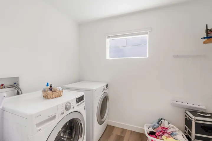 Dedicated laundry area featuring a window, light wood-finish flooring, and white walls