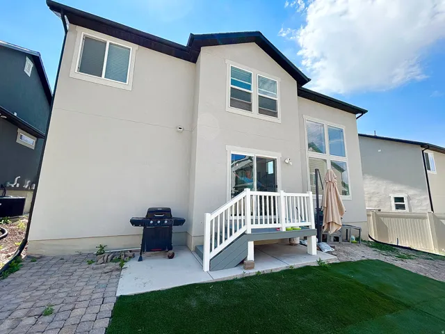 Rear exterior featuring a deck with white railings, a sliding glass door, and a multi-pane window