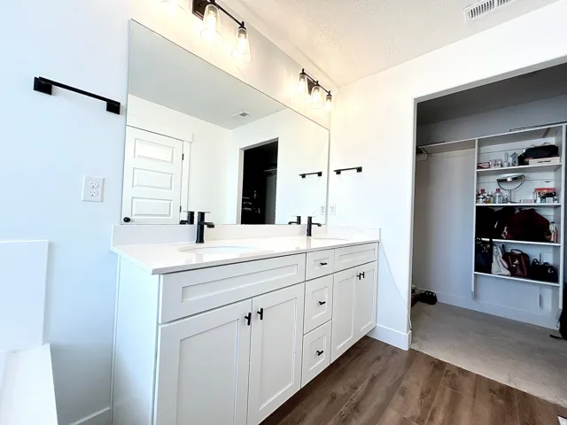 Dual vanity featuring white shaker cabinetry, white countertop, and matte black fixtures