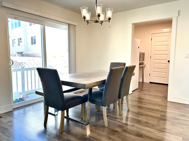 Dining area featuring wood-finish flooring, a contemporary chandelier, and ample natural light from the sliding glass door