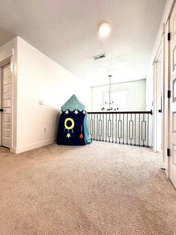 Carpeted loft area featuring a contemporary iron railing and recessed lighting
