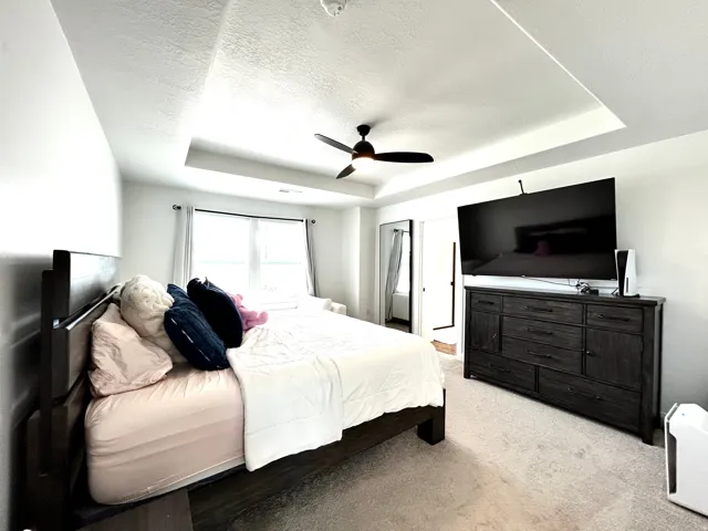Spacious bedroom featuring a tray ceiling, recessed lighting, and a ceiling fan