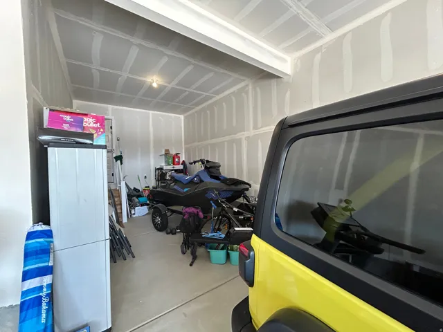 Spacious garage featuring unpainted drywall walls and ceiling, concrete flooring, and an exposed light fixture