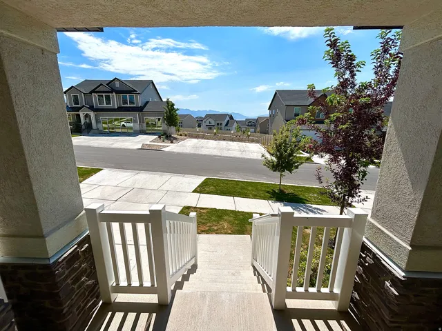 Front porch featuring a concrete surface, white railing, and stone veneer accents