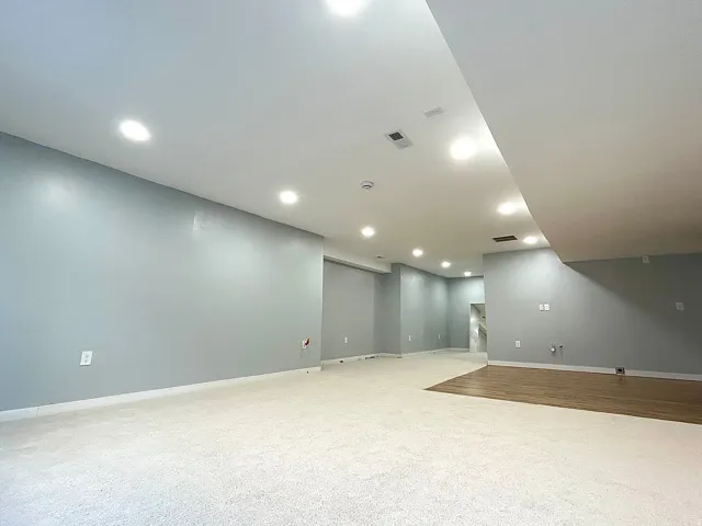 Spacious room featuring recessed lighting, light gray walls, a combination of carpeting and wood-finish flooring, and a drop ceiling