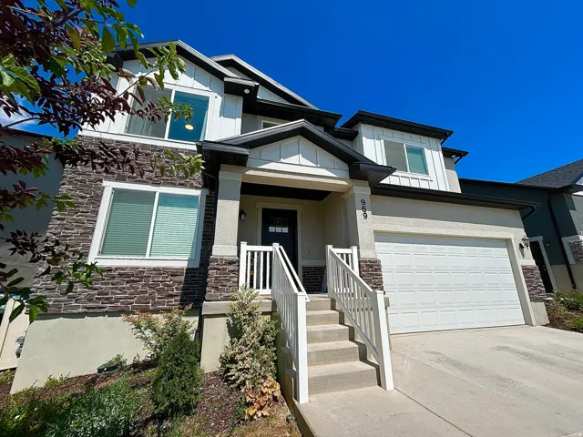 Contemporary exterior with stone veneer and horizontal siding accents, featuring a prominent front entry with white railings and an integrated two-car garage