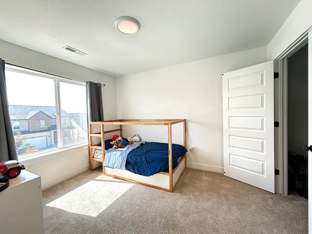 Bright room featuring a large horizontal window, light-colored carpet flooring, a five-panel interior door, and a flush-mount ceiling light fixture