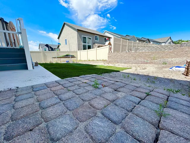 Paver patio with a fresh sod lawn and a concrete deck area