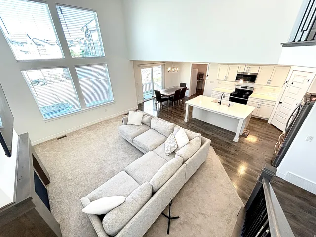 Open-concept main level featuring a two-story ceiling, a kitchen island with seating, stainless steel appliances, and wood-finish flooring