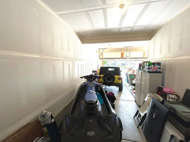 Attached garage featuring a concrete floor and a partially finished ceiling