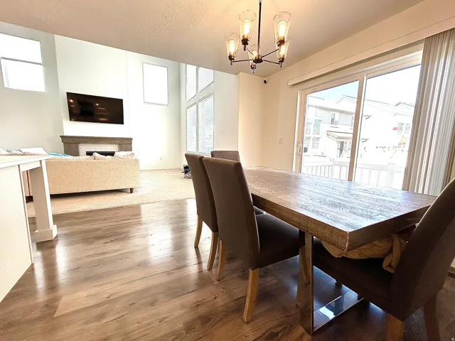 Open-concept dining area featuring wood-finish flooring, a contemporary chandelier, and direct access to the outdoor space via a sliding glass door