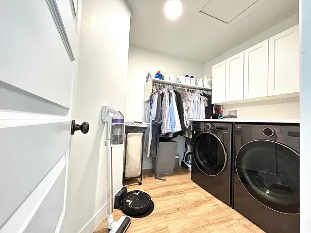 Laundry area featuring wood-finish flooring, white cabinetry, integrated countertop, and built-in clothes storage with shelving