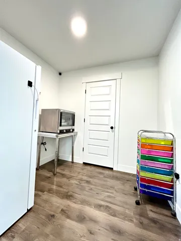 Hardwood-style flooring with a modern paneled door featuring black hardware