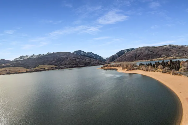 Expansive waterfront property featuring a sandy shoreline and surrounding mountain ranges