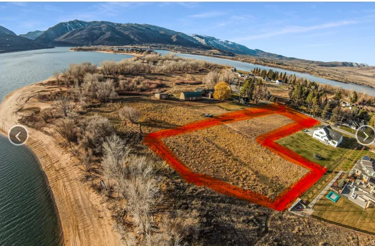 Expansive land parcel with water frontage, featuring a clear, buildable area and distant mountain backdrop