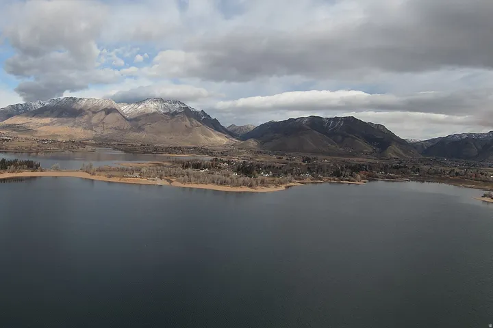 Expansive lake with surrounding land and distant mountains featuring snow-capped peaks