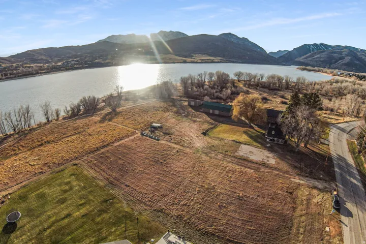 Expansive property parcel featuring a large lakefront, mountain backdrop, and direct paved road access