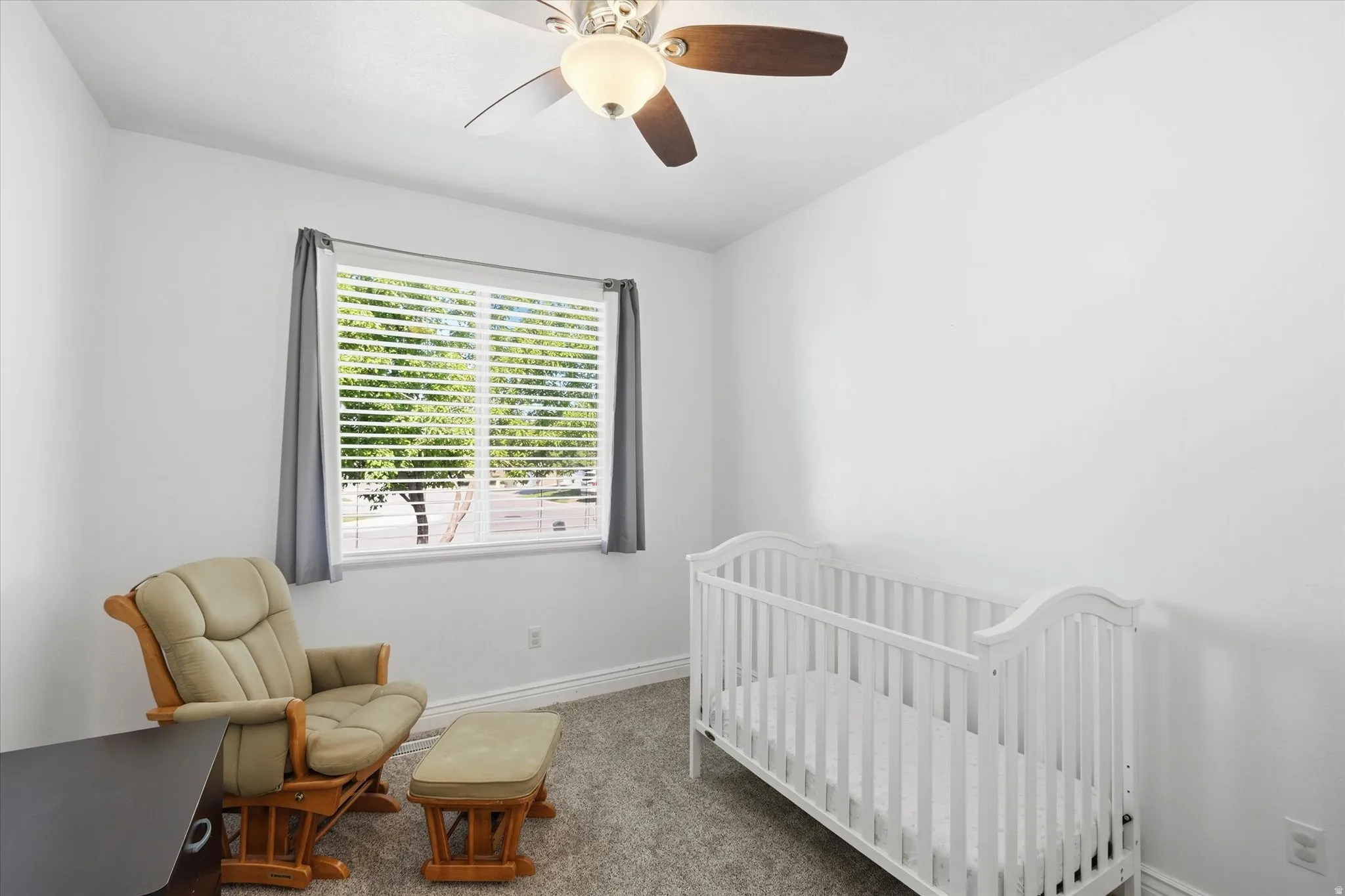 Carpeted interior space featuring a ceiling fan with integrated lighting, a window with horizontal blinds, and base molding