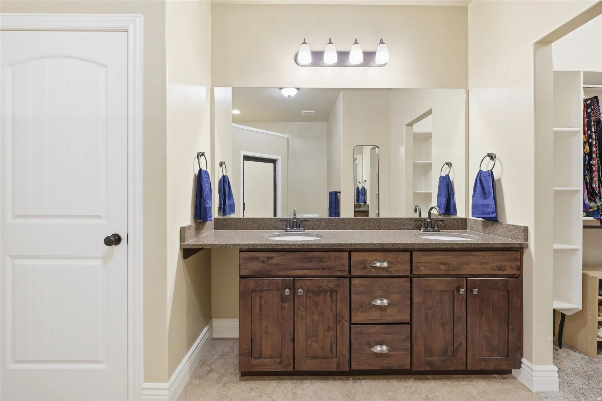 Double vanity featuring a stone-finish countertop, dual sinks with dark-finish faucets, and a large mirror