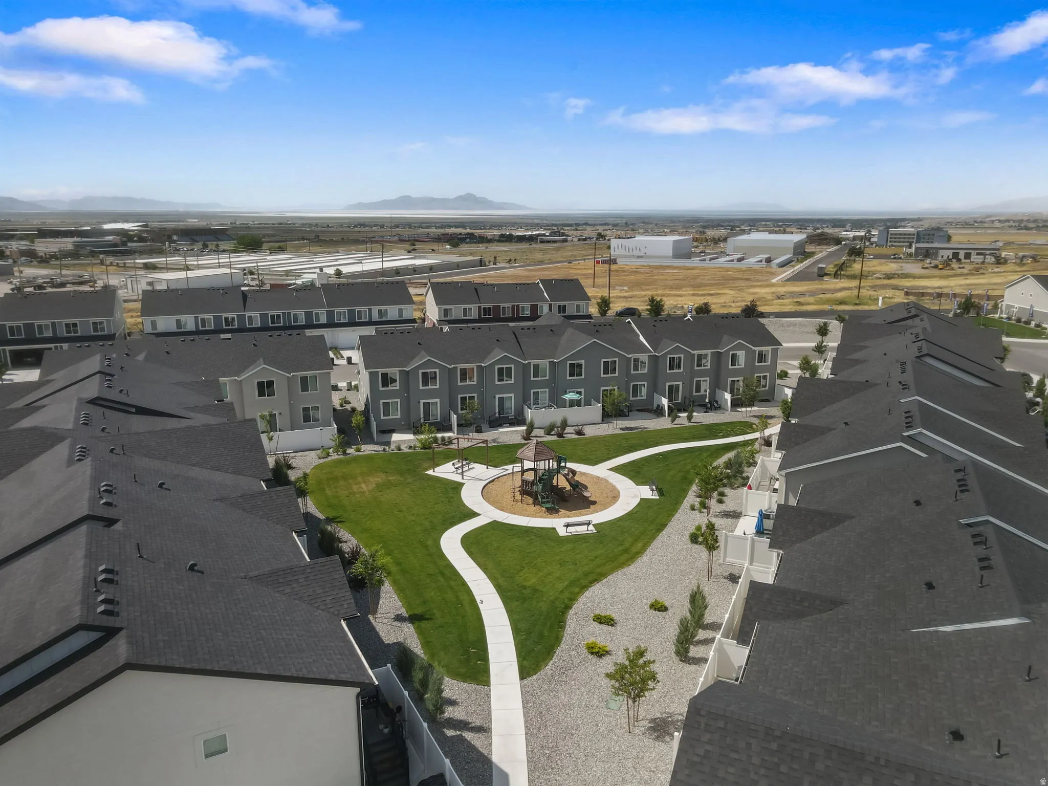 Central community green space featuring a playground, manicured lawn, and paved walking paths