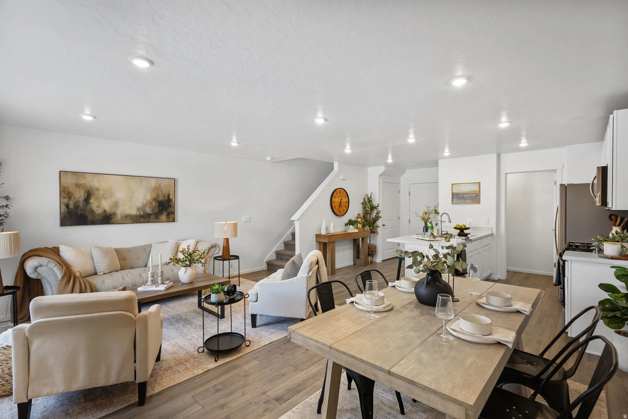 Open-concept living area featuring wood-finish LVP flooring throughout, recessed lighting, and a white kitchen with a central island