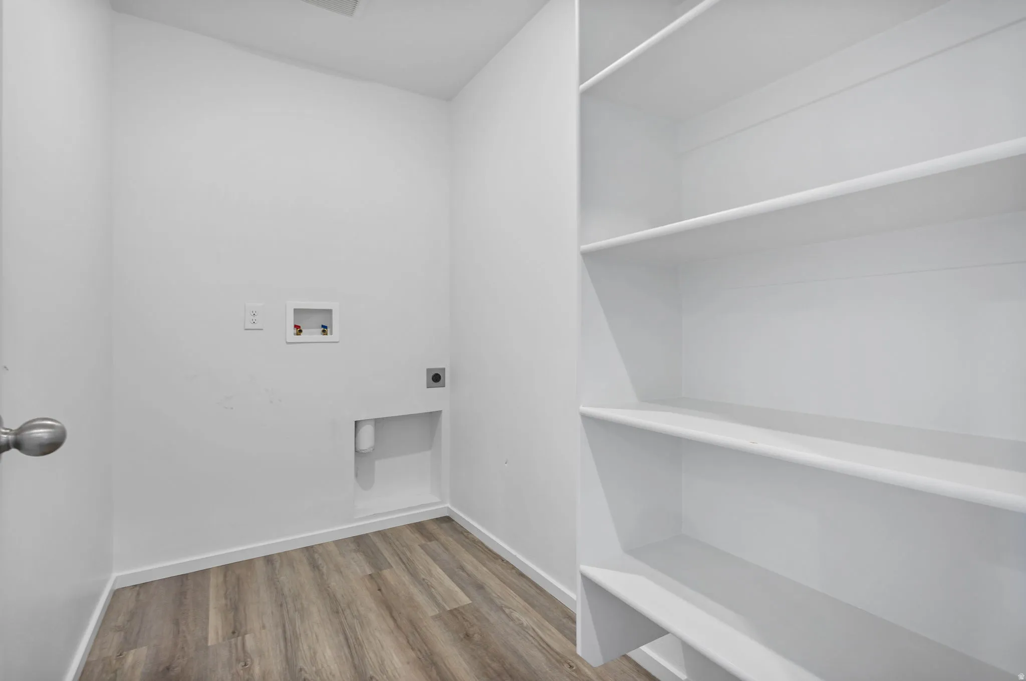Dedicated utility space featuring wood-finish LVP flooring, built-in shelving, and white walls