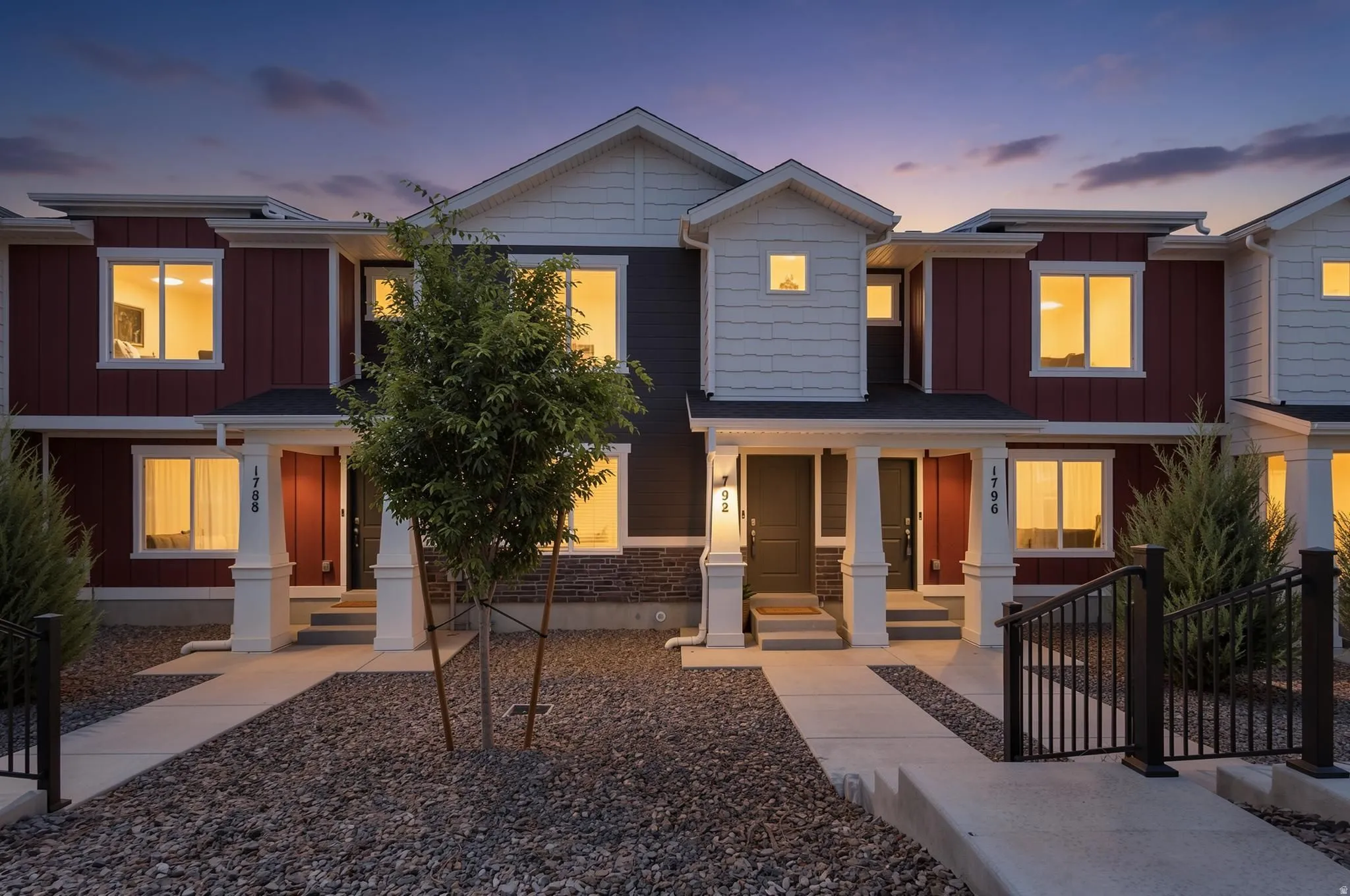 Contemporary townhome exteriors featuring vertical and horizontal siding, stone accents, white trim, and covered front entrances