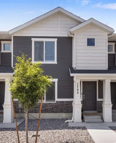 Contemporary town home exteriors featuring vertical and horizontal siding, stone accents, white trim, and covered front entrances