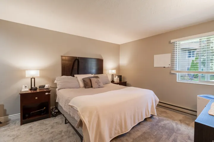 Carpeted bedroom featuring a large window with horizontal blinds, neutral wall tones, and recessed ceiling lighting