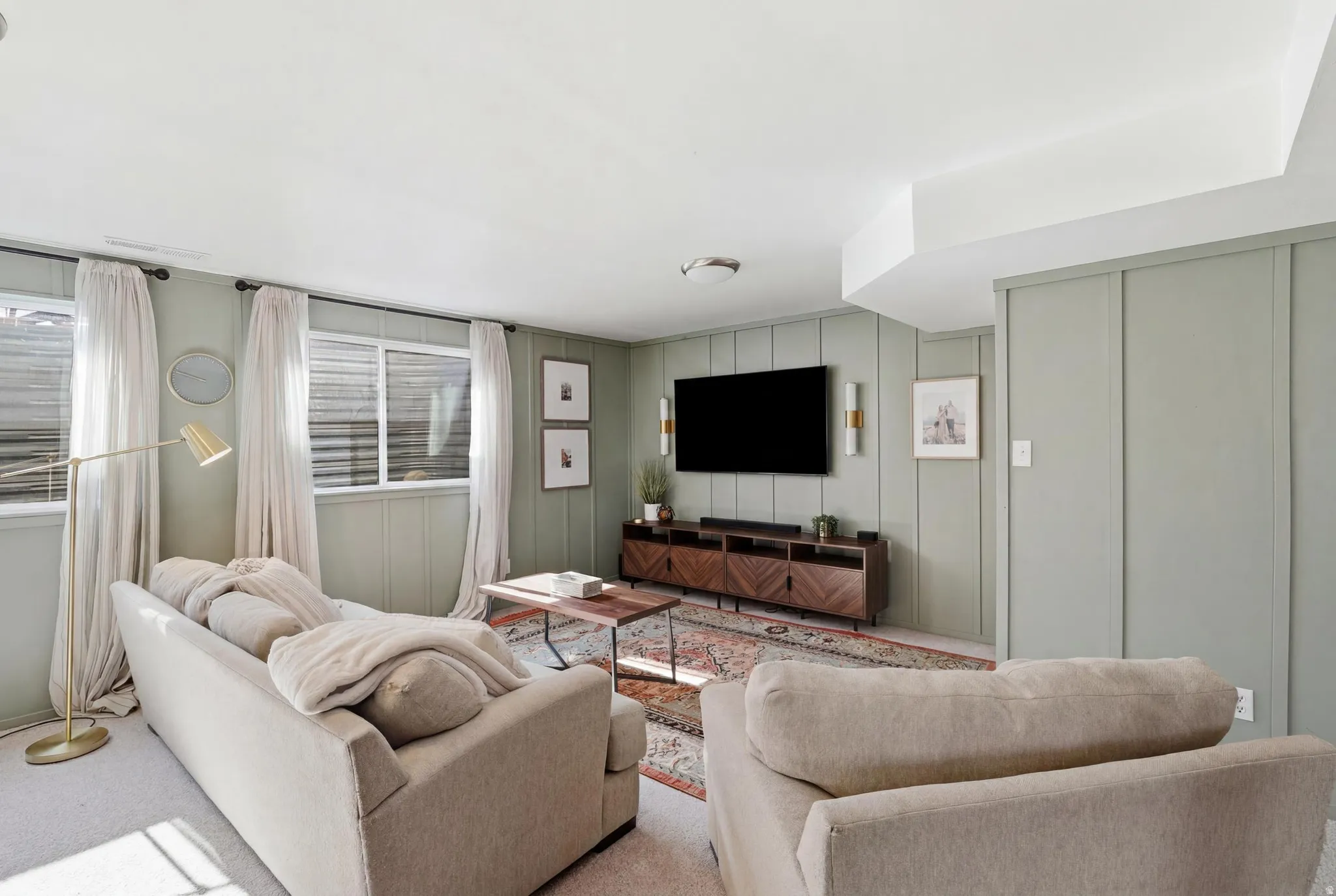 Finished basement living area featuring board and batten accent walls, dual windows, and recessed lighting