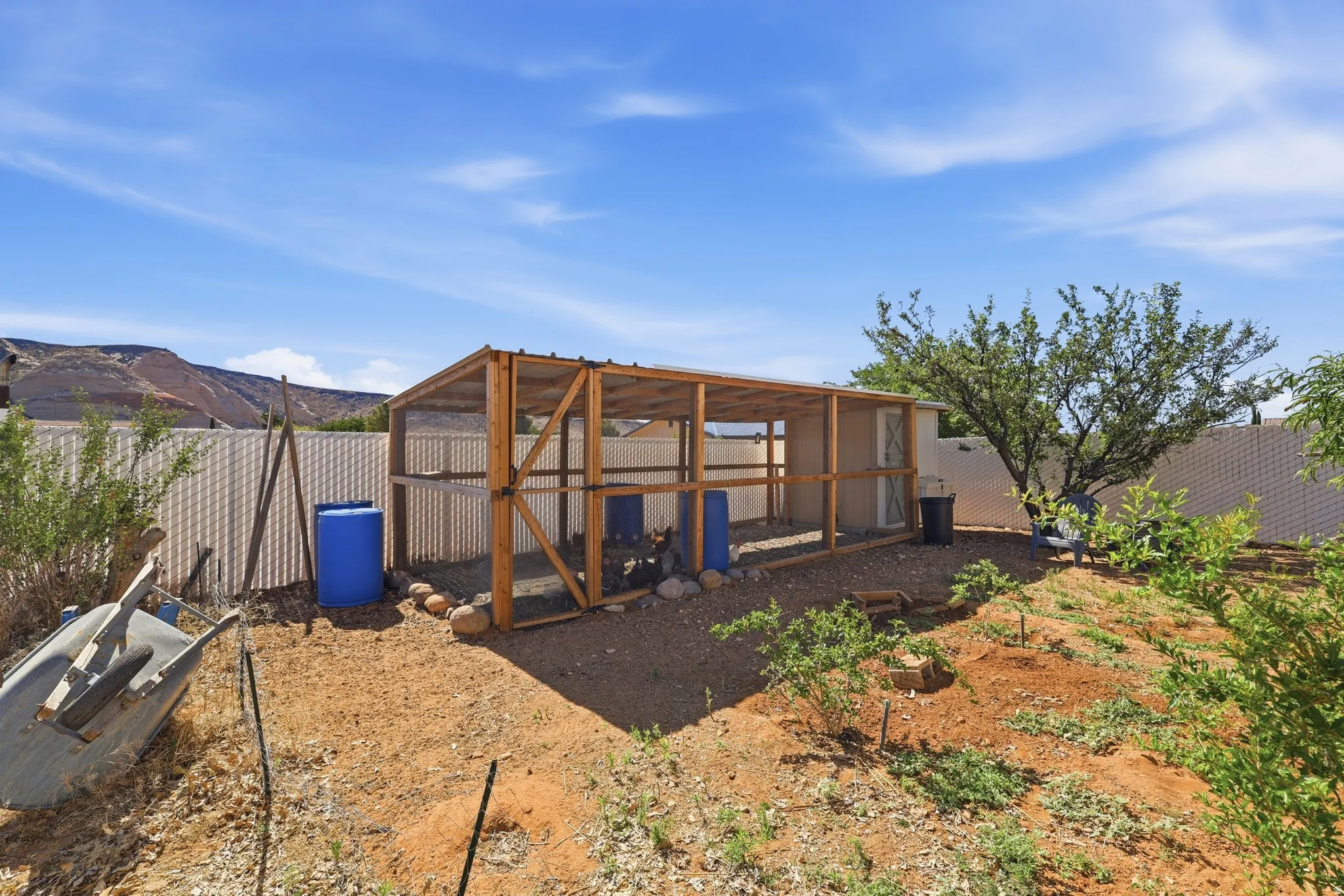 Expansive outdoor space featuring a large wooden framed structure, gravel ground cover, and a surrounding privacy fence