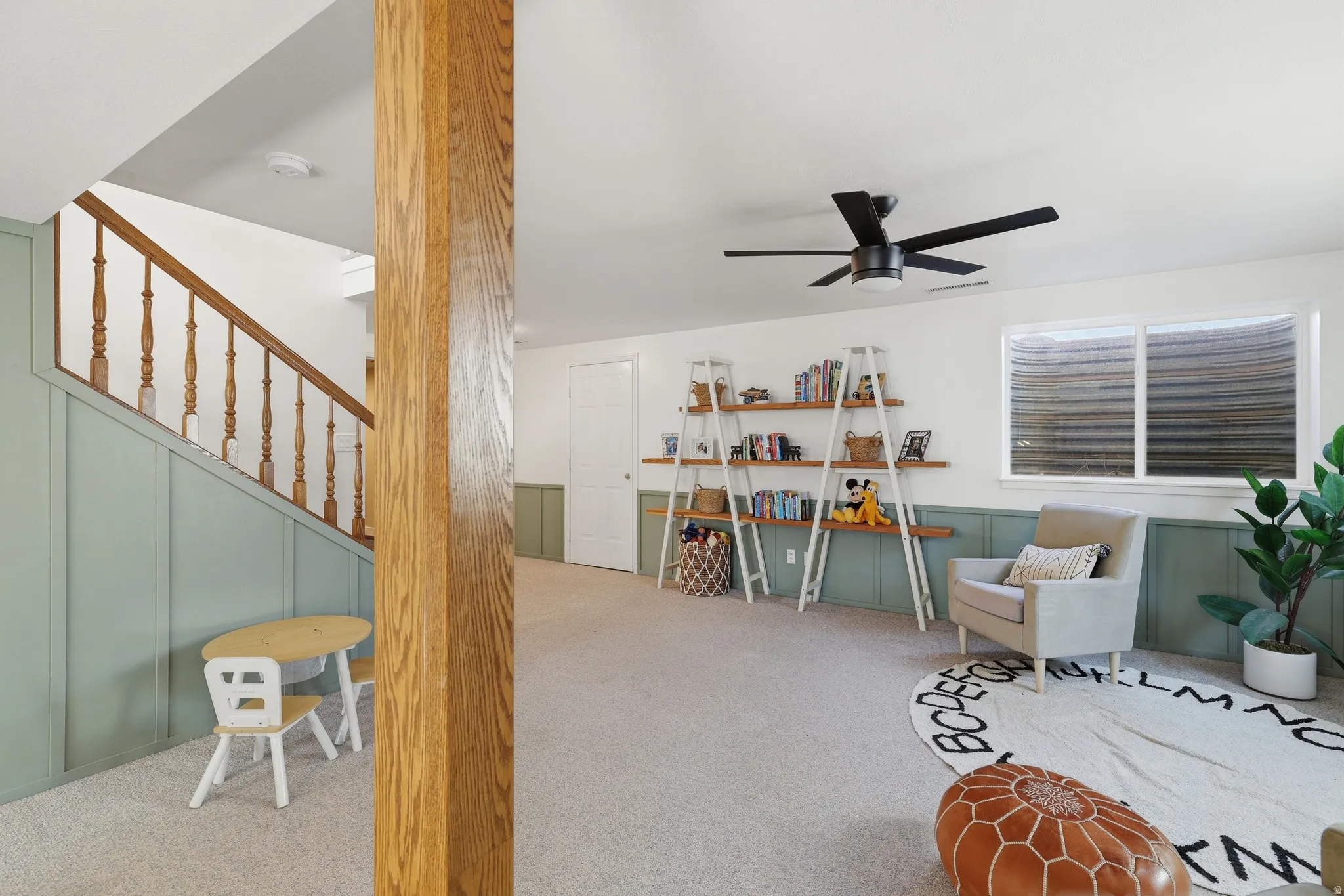 Finished lower level featuring light green wainscoting, white walls, and light-colored carpeting