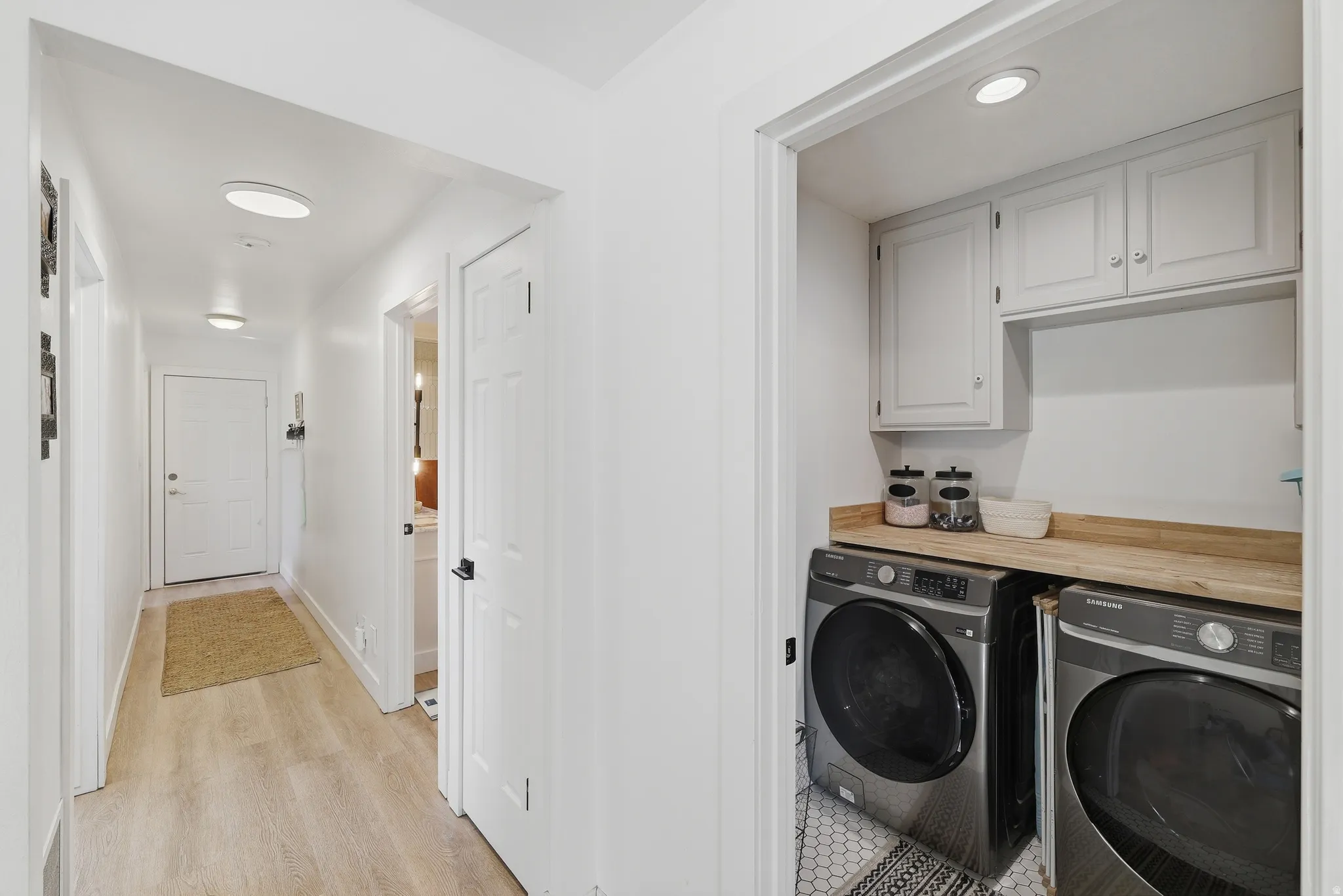 Dedicated laundry area with upper cabinetry and a wood-finish countertop