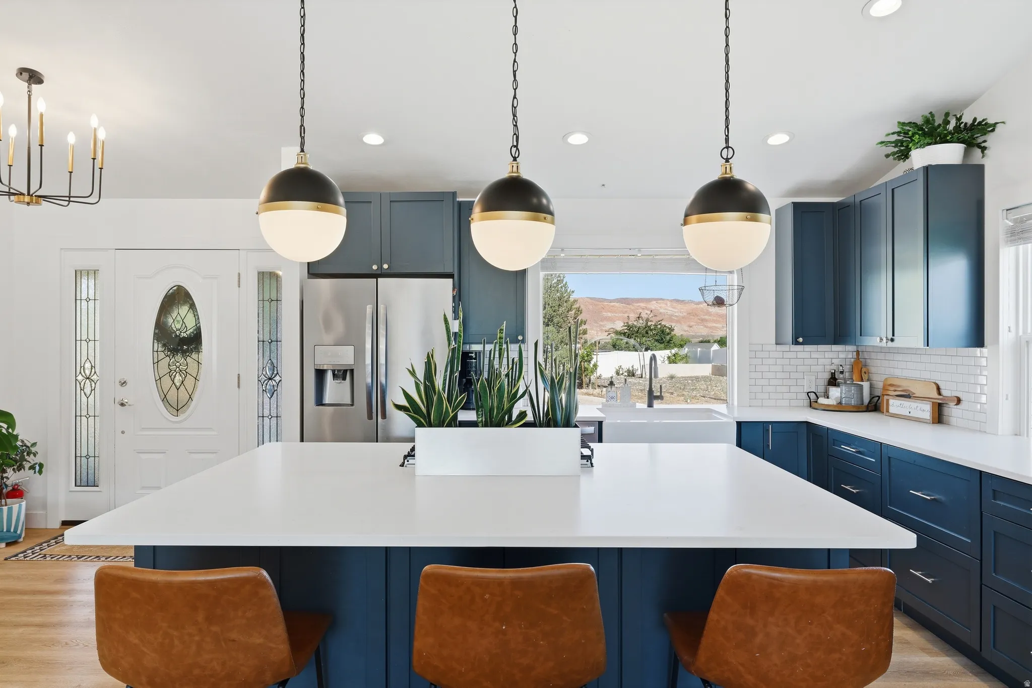 Kitchen featuring a large island with three pendant lights, blue cabinetry, white countertops, a subway tile backsplash, and stainless steel appliances