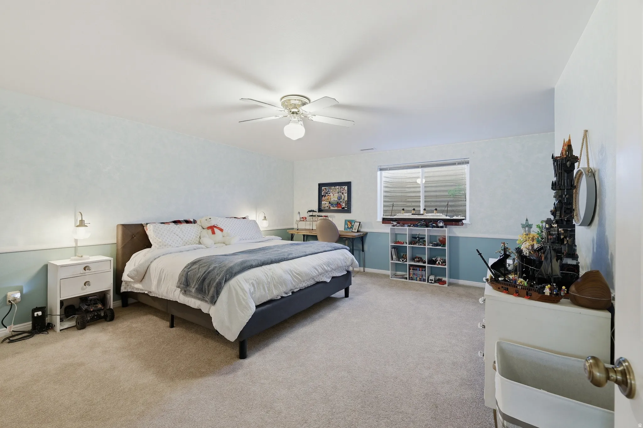 Spacious room featuring neutral carpeting, a ceiling fan with integrated lighting, and a horizontal window with blinds