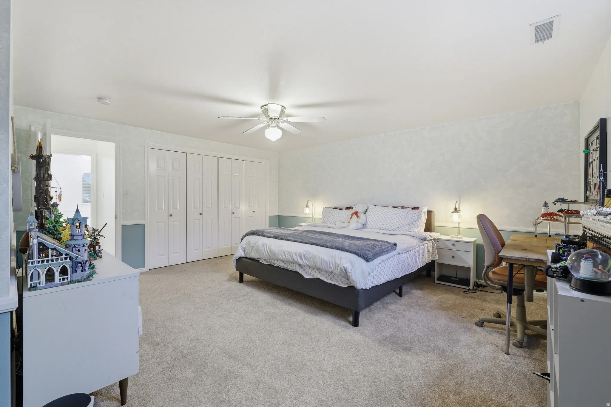 Carpeted room featuring a ceiling fan, white bi-fold closet doors, and light-colored wall finishes