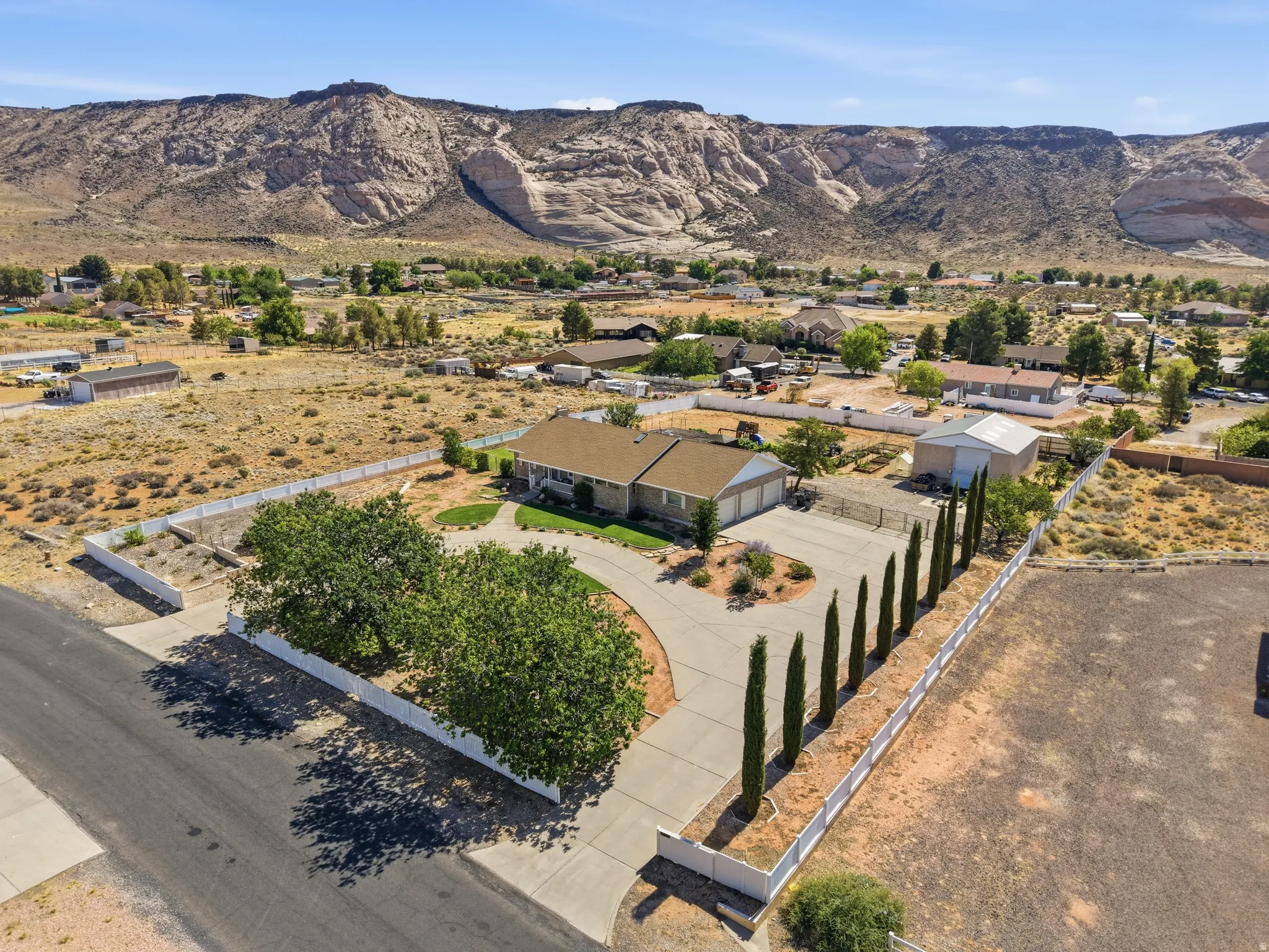 Expansive property featuring a single-story residence, detached garage/outbuilding, and a paved circular driveway