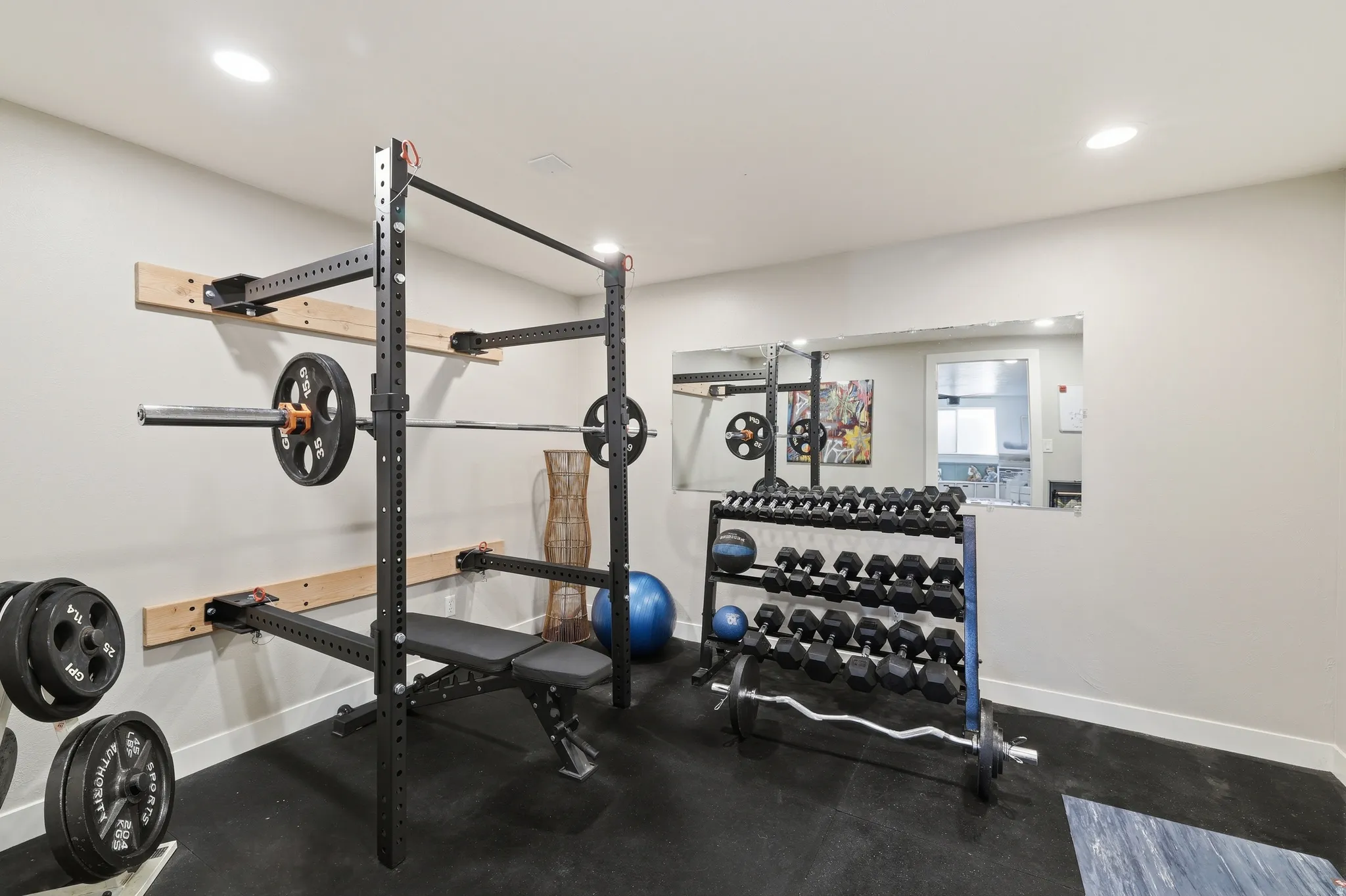 Dedicated fitness space featuring rubberized flooring, recessed lighting, and a wall-mounted mirror