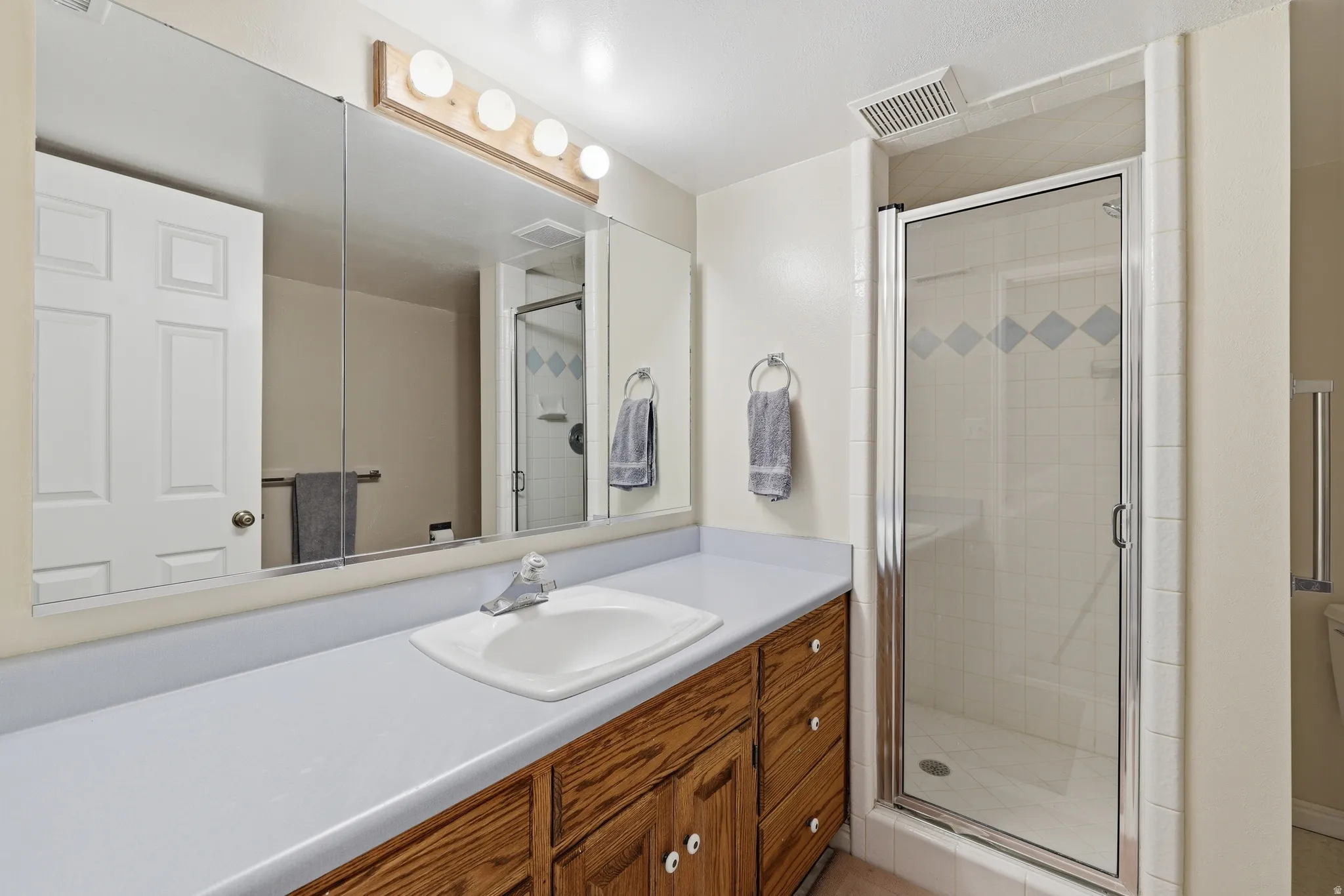 Bathroom vanity featuring a white drop-in sink and wood-finish cabinetry