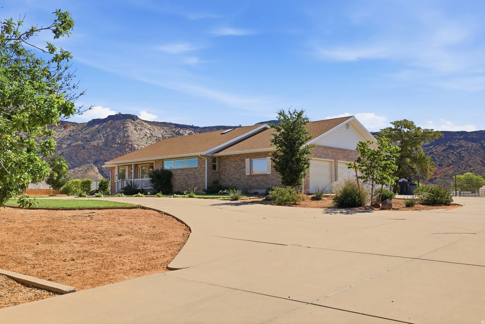 Brick exterior residence with an attached two-car garage, a covered front porch, and a paved driveway