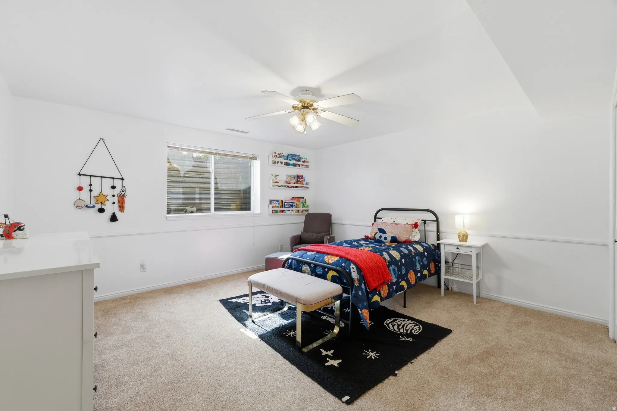 Carpeted room featuring a ceiling fan with light, a window with blinds, and white walls with wainscoting