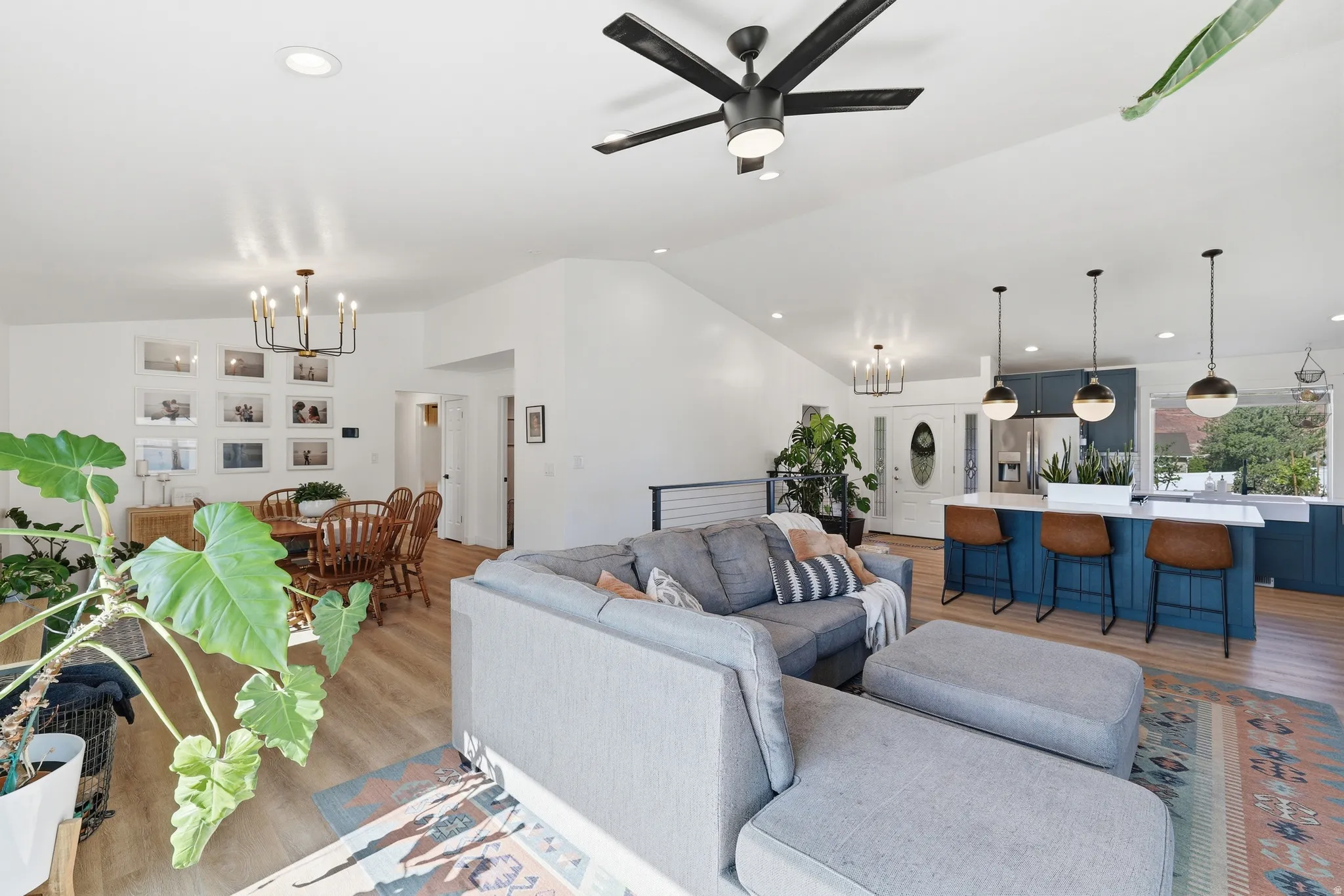 Vaulted ceilings and recessed lighting illuminate an open-concept living space featuring wood-finish flooring throughout