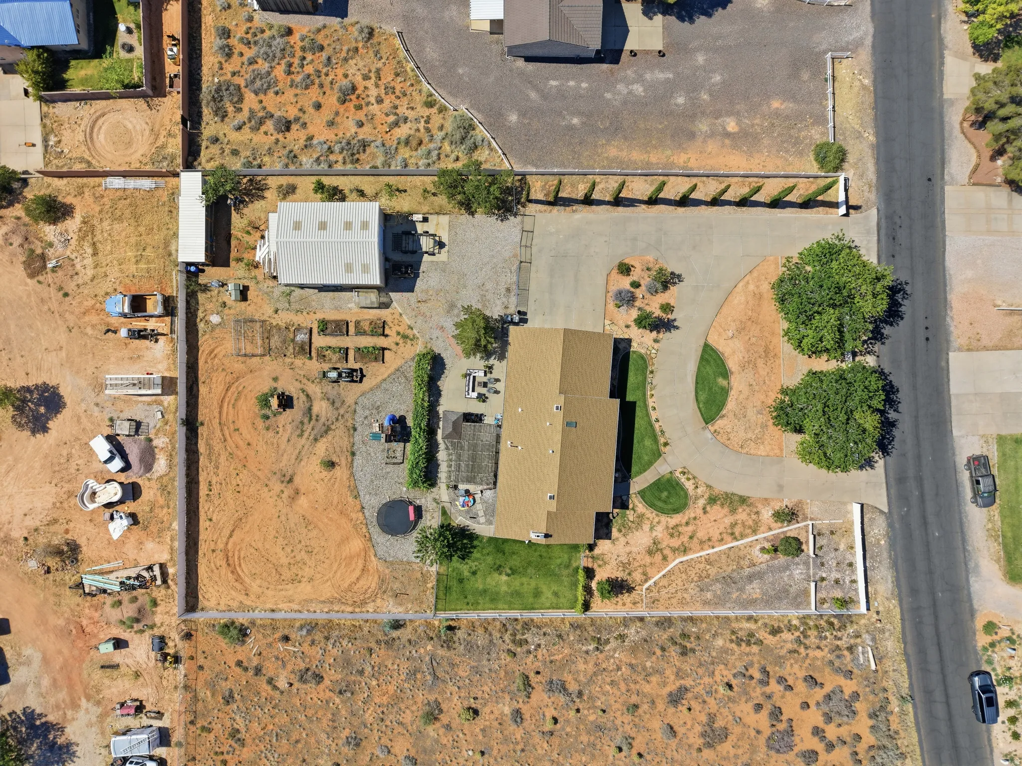 Expansive property featuring a main residence with a brown shingle roof, a separate large outbuilding with a light-colored metal roof, and a circular driveway