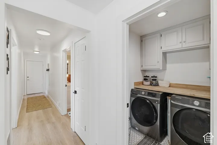 Dedicated laundry area with upper cabinetry and a wood-finish countertop