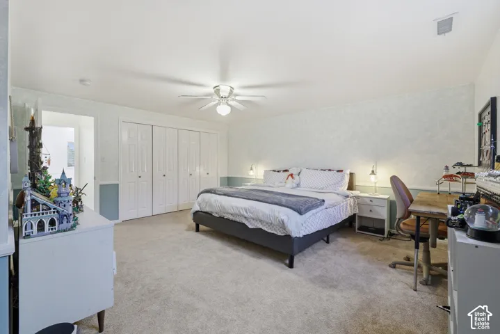 Carpeted room featuring a ceiling fan, white bi-fold closet doors, and light-colored wall finishes