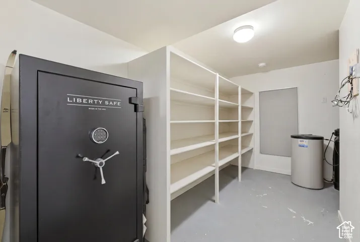 Dedicated storage room featuring a large built-in shelving system, a window with a roller shade, and an overhead flush-mount light fixture