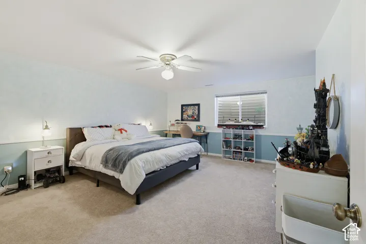 Spacious room featuring neutral carpeting, a ceiling fan with integrated lighting, and a horizontal window with blinds
