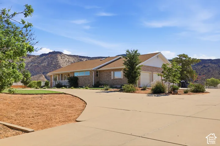 Brick exterior residence with an attached two-car garage, a covered front porch, and a paved driveway
