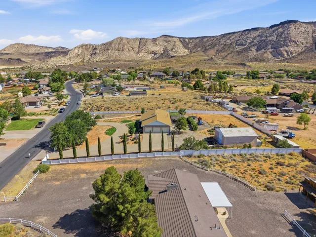 Expansive property featuring a curved driveway, mature landscaping, substantial outbuilding, and a mountain backdrop