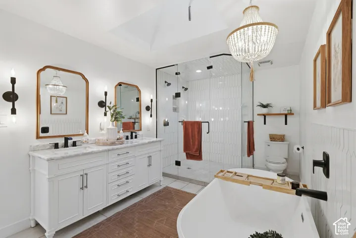 Bright bathroom featuring a double vanity with stone countertop, freestanding soaking tub, and a glass-enclosed shower with vertical tile work